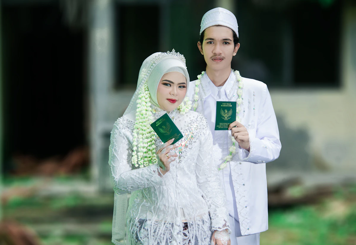 A newlywed couple in traditional attire holding their marriage books